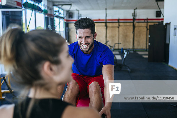 Lächelnder Mann sieht Frau im Fitnessstudio an