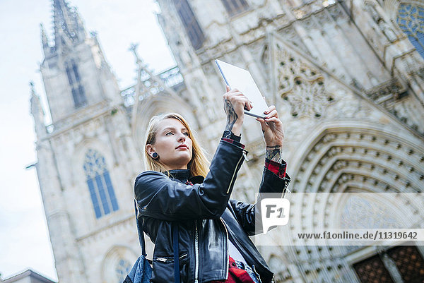 Spain  Barcelona  young woman taking picture with tablet in front of cathedral