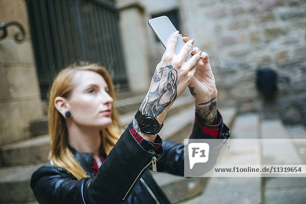 Tattooed woman's hands taking selfie with cell phone