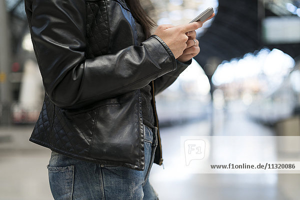 Woman using cell phone at train station