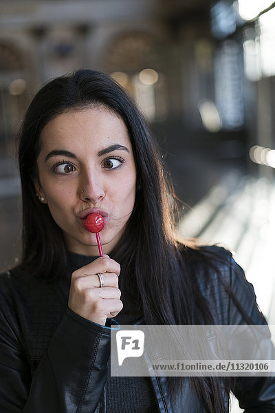 Porträt einer jungen Frau mit Lollipop ziehenden Gesichtern