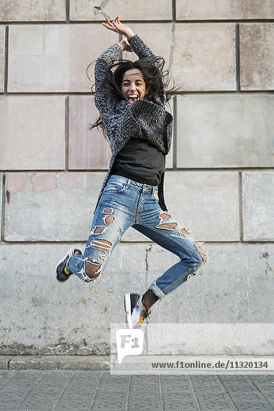 Porträt einer überschwänglichen jungen Frau  die umher springt.
