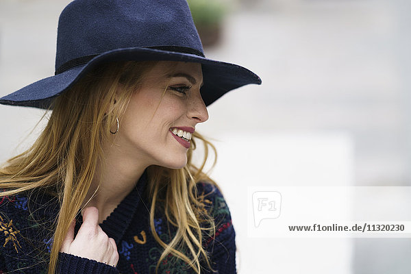 Lächelnde junge Frau mit blauem Hut