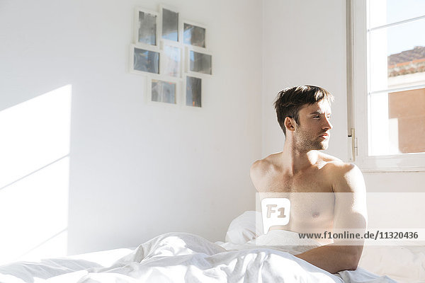 Young man sitting in bed