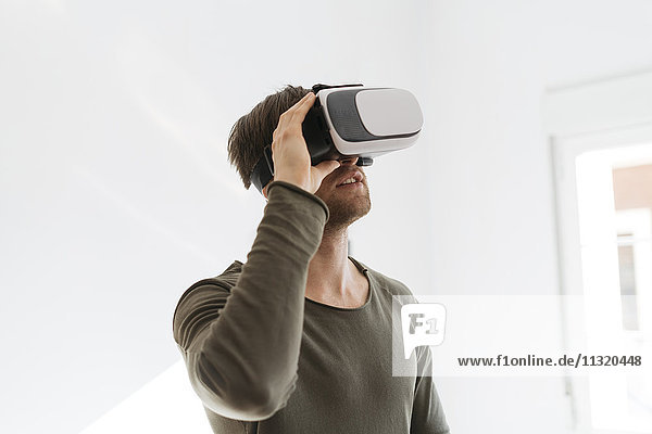 Young man wearing virtual reality glasses at home