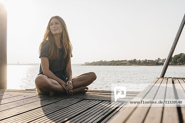 Portrait of smiling young woman relaxing on jetty