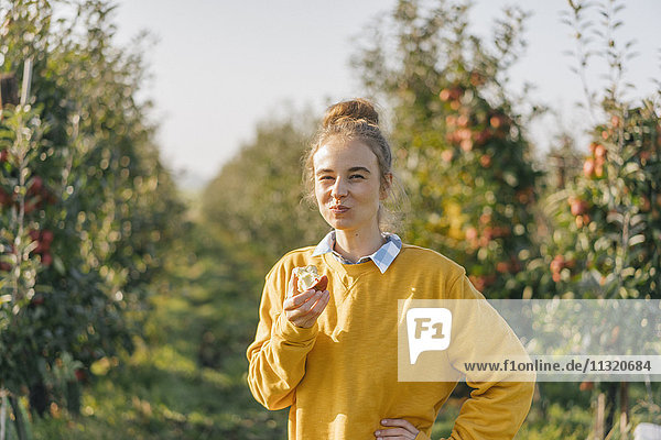Junge Frau beim Essen eines Apfels im Apfelgarten