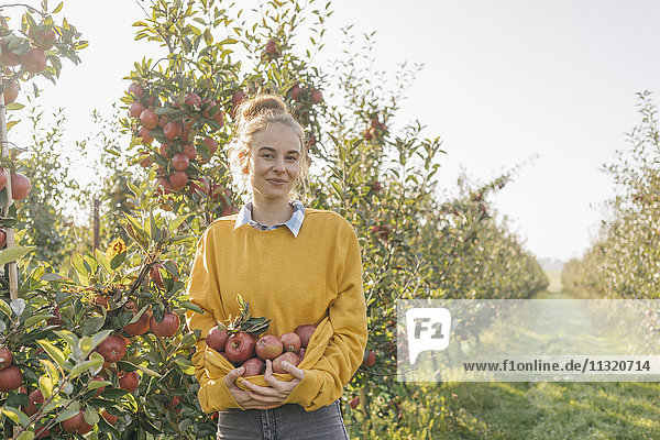 Junge Frau mit Äpfeln im Obstgarten