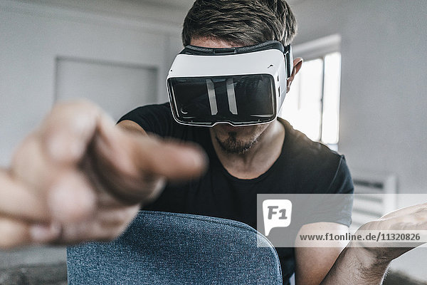 Man sitting on chair wearing VR glasses