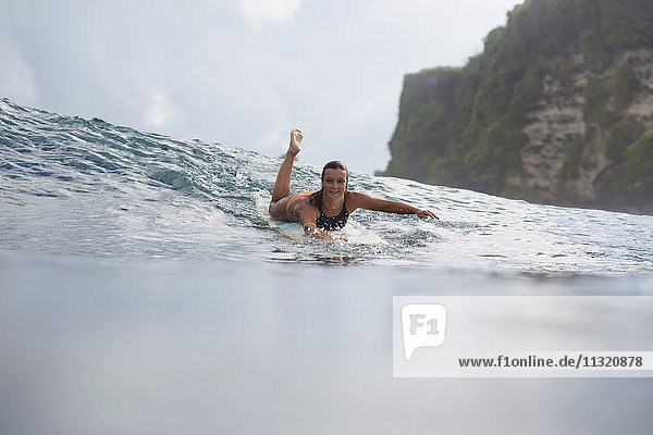 Indonesien  Bali  Frau auf dem Surfbrett im Meer liegend