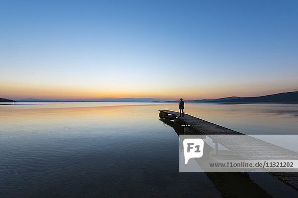 Italien  Umbrien  Trasimeno-See  Silhouette des Mannes  der am Steg steht und den Sonnenuntergang beobachtet.