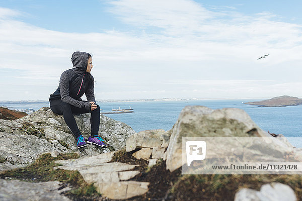 Ireland  Howth  female athlete sitting at cliff coast
