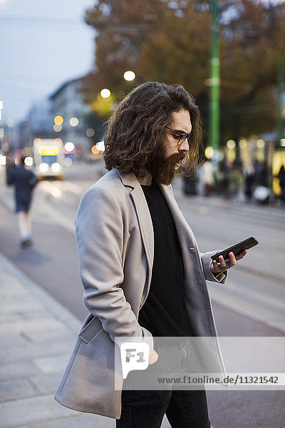 Stylish young man in the city checking cell phone