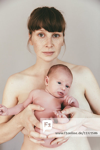 Portrait of nude mother holding her newborn baby