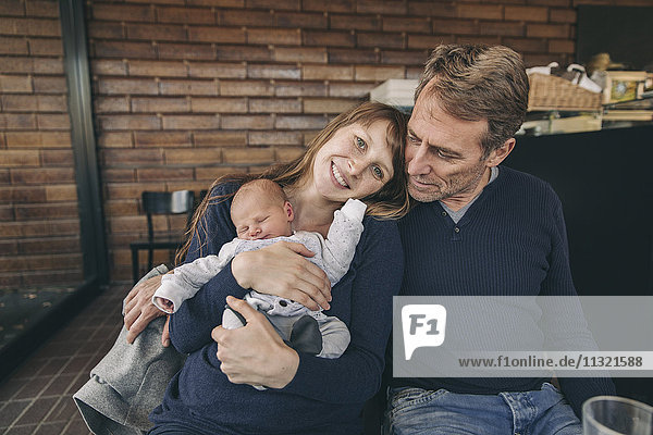Mother and father with newborn baby sitting in cafe