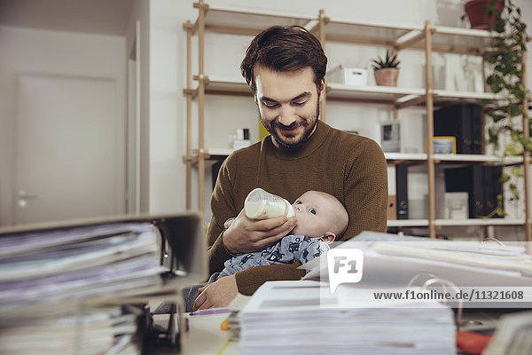 Vater füttert sein Baby im Home Office