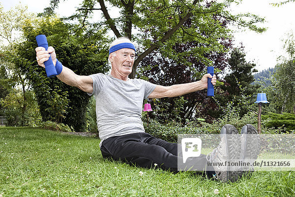 Senior Mann beim Fitnesstraining mit Kurzhanteln im Garten