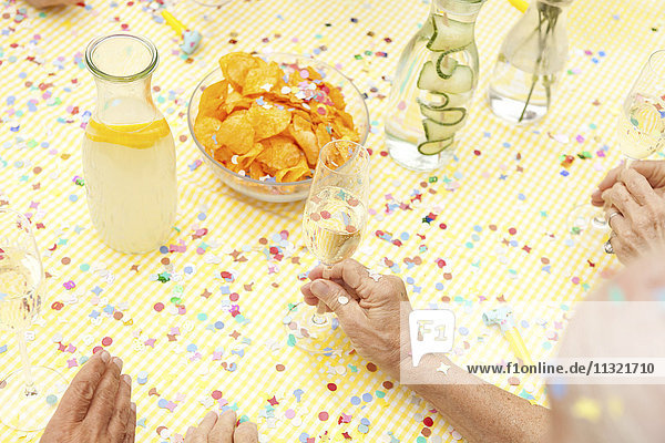 Seniorenfeier am Tisch mit Wasser  Champagner und Kartoffelchips
