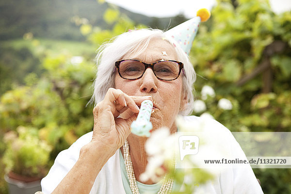 Senior Frau bläst Partygebläse