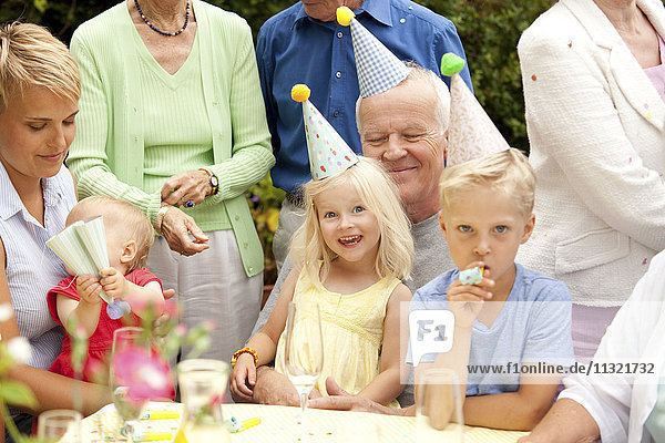 Erweiterte Familie und Freunde bei der Geburtstagsfeier im Garten