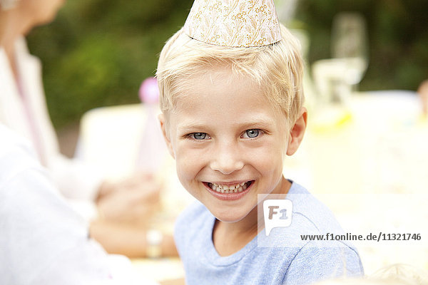 Blonder Junge mit Partyhut auf der Geburtstagsfeier