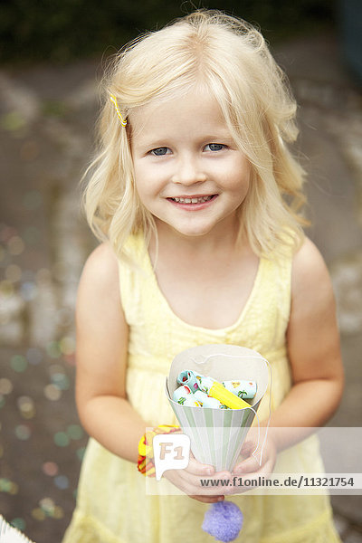 Kleines Mädchen mit Partyhut gefüllt mit Party-Blowouts