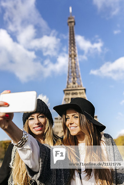 Frankreich  Paris  zwei lächelnde Frauen  die einen Selfie mit dem Eiffelturm im Hintergrund nehmen.