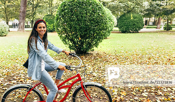 Lächelnde junge Frau beim Radfahren im Park