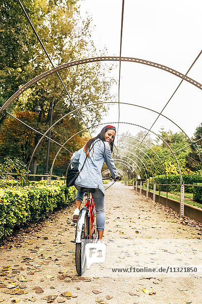 Lächelnde junge Frau beim Radfahren im Park