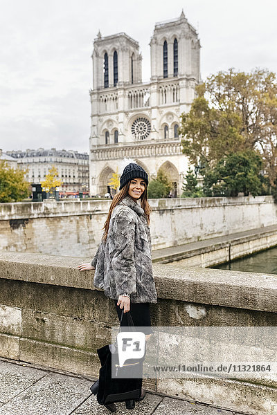 Frankreich  Paris  lächelnde junge Frau vor Notre Dame stehend