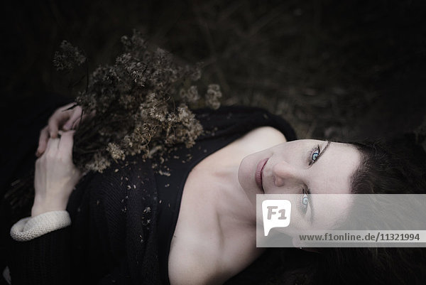 Porträt einer melancholischen Frau auf dem Waldboden liegend
