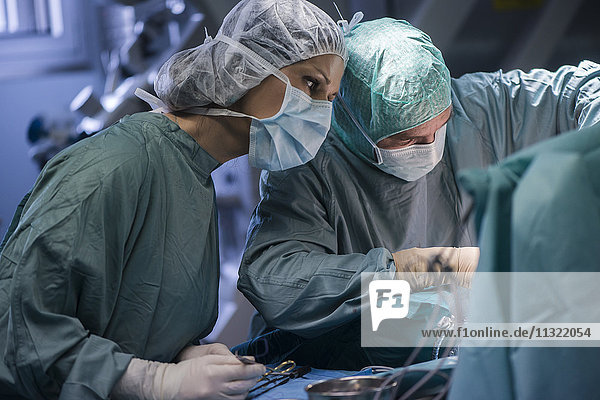 Neurochirurg mit Krankenschwester  die Operationswunde schließt