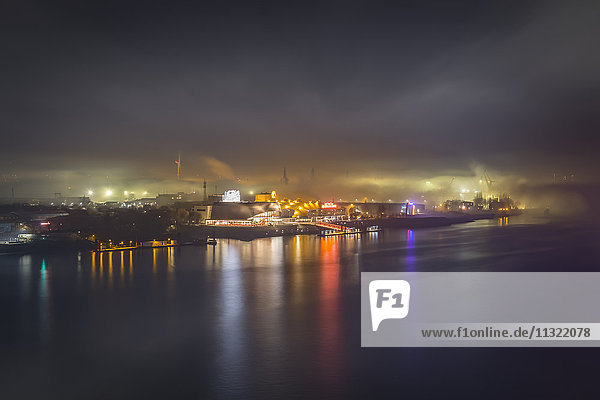 Deutschland  Hamburg  Blick auf den Hafen mit beleuchtetem Musiktheater im Nebel bei Nacht