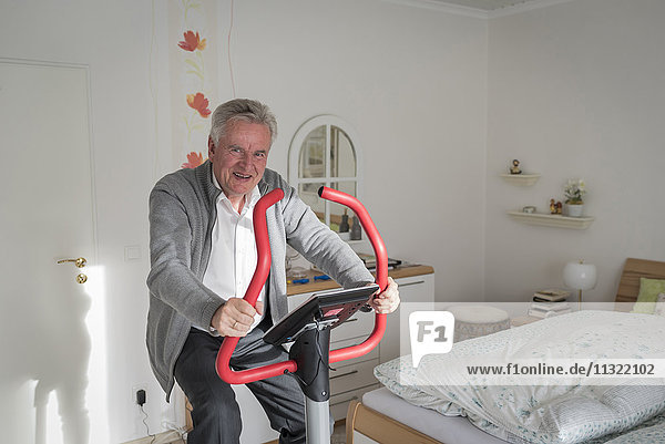 Senior man training at home at exercise machine