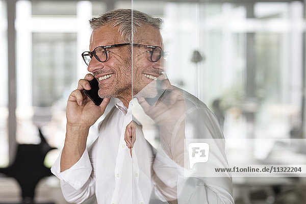 Smiling businessman on cell phone in office
