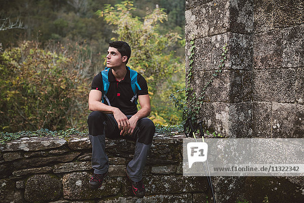 Wanderer sitzend auf einer Steinmauer in der Natur