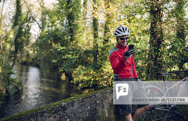 Mountainbiker beim Fotografieren im Wald mit seinem Smartphone