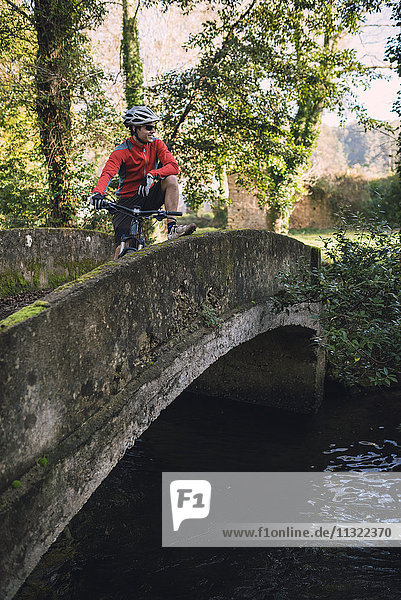 Young mountain biker standing on bridge