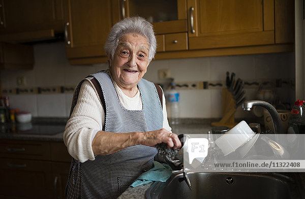 Seniorin beim Geschirrspülen in der Küche