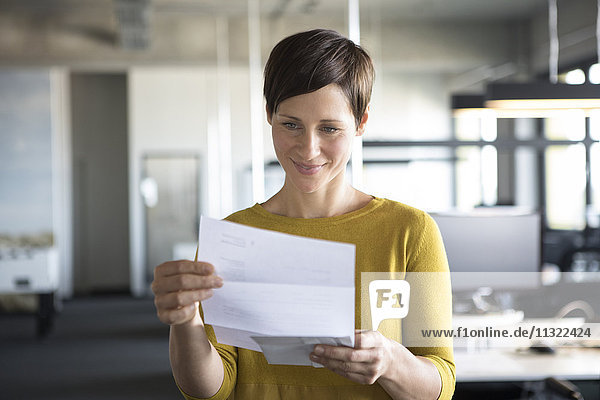 Geschäftsfrau im Büro mit Blick auf Papier