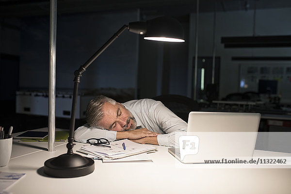 Erschöpfter Geschäftsmann schläft auf dem Bürotisch