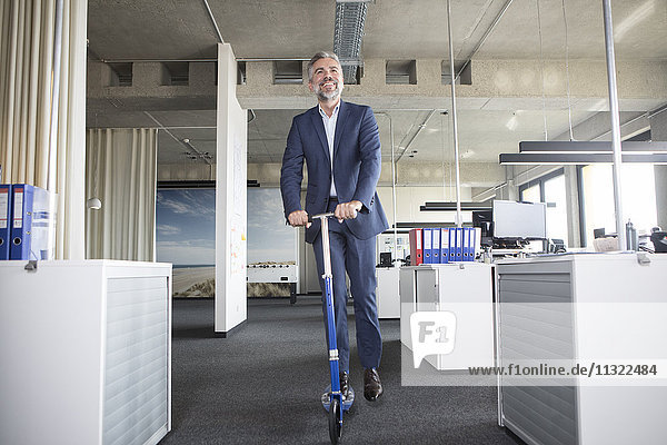 Businessman on scooter in office