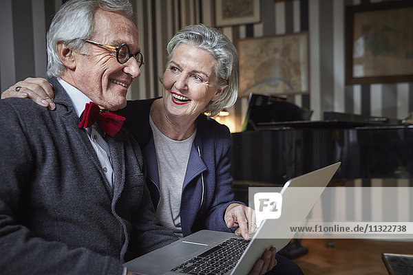 Fröhliches Seniorenpaar mit Laptop zu Hause