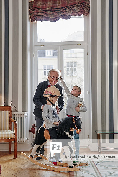 Großvater und Enkel spielend mit Schaukelpferd