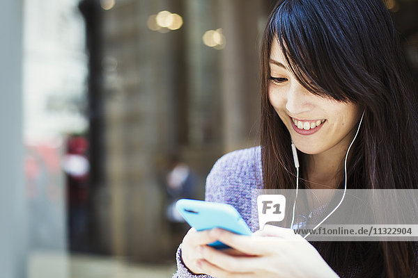 Junge Japanerin genießt einen Tag in London und benutzt ein Smartphone.
