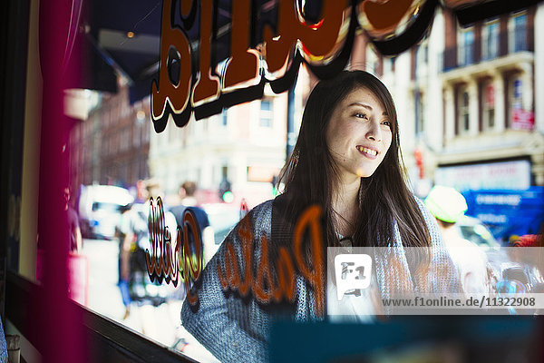 Young Japanese enjoying a day out in London  walking past a shop window.