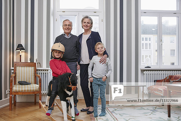 Großeltern und Enkelkinder mit Schaukelpferd im Wohnzimmer
