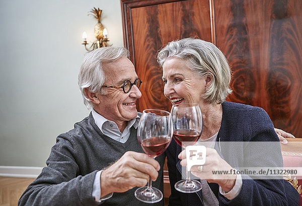 Smiling senior couple clinking red wine glasses