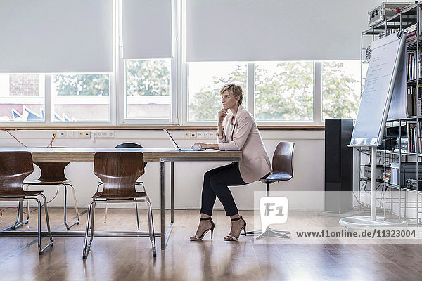 Businesswoman using laptop in modern conference room