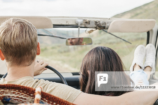 Ein Ehepaar auf einer Autofahrt in den Bergen,  sitzend in einem offenen Jeep mit offenem Dach.